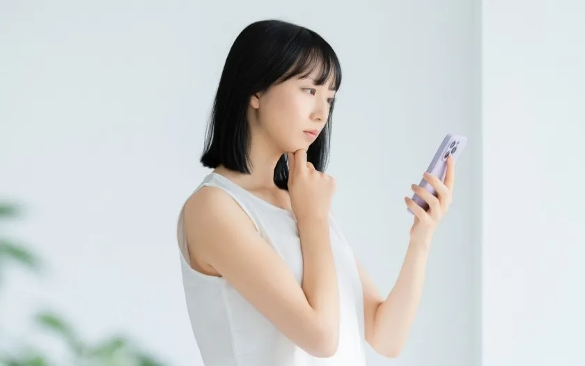 スマートフォンをみて悩む女性