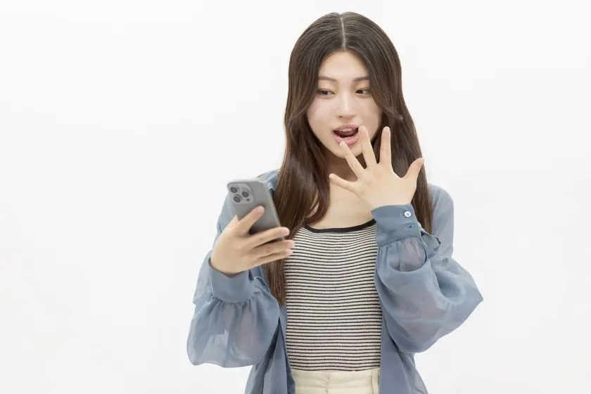 携帯を見て驚く女性