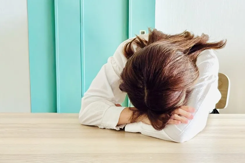 机にうつ伏せて泣いている女性