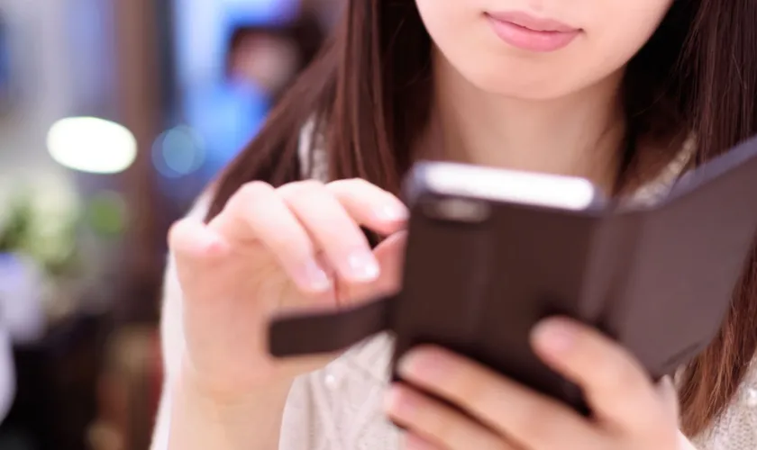 カフェでスマートフォンを触る女性の画像