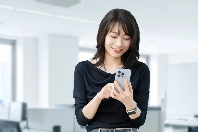 笑顔でスマートフォンを操作する女性