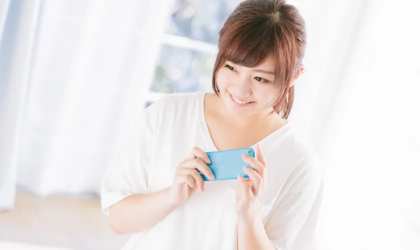 スマートフォンを持って嬉しそうに微笑む女性