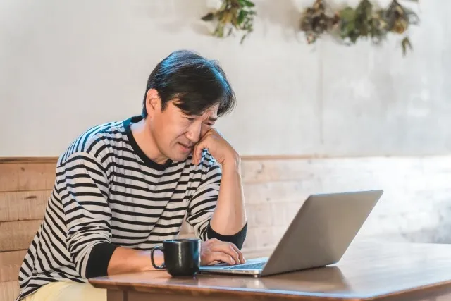 PCをみて悩む男性