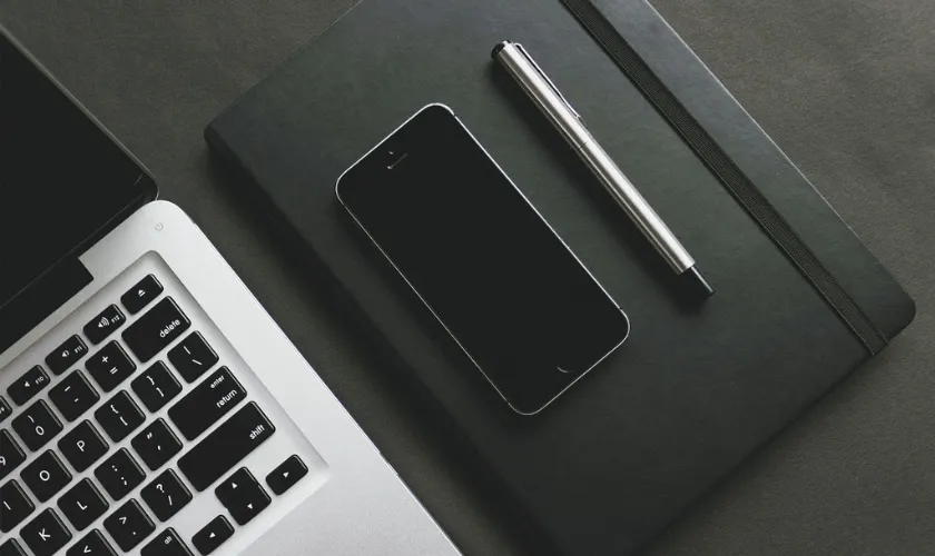 スマートフォンとノート、ボールペンの写真