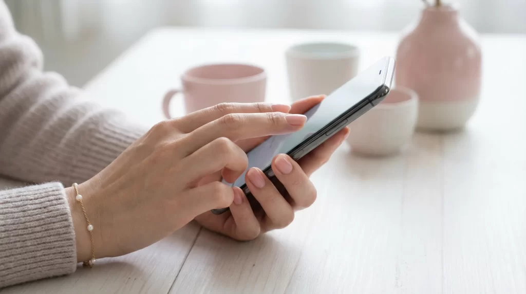 スマートフォンでメッセージアプリを操作する女性の手元。