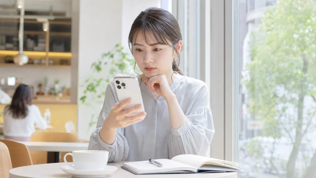 女性がスマートフォンで複数のアプリを比較検討しているシーン